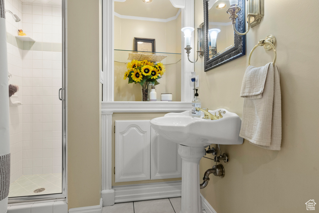 Bathroom with crown molding, baseboards, tile patterned flooring, and a stall shower
