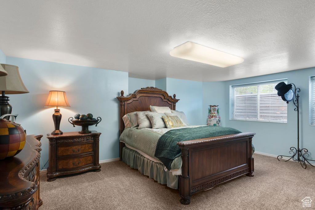 Bedroom featuring carpet floors, a textured ceiling, and baseboards