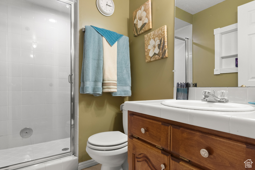 Bathroom with vanity, a stall shower, and toilet