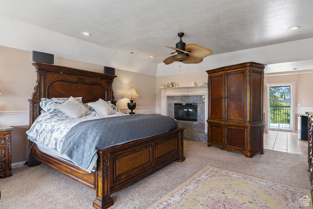 Bedroom featuring a textured ceiling, light carpet, ceiling fan, and a fireplace