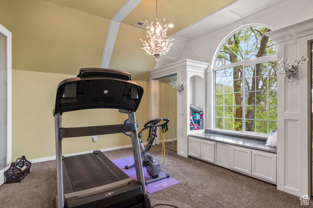 Workout room with visible vents, dark carpet, lofted ceiling, and a notable chandelier