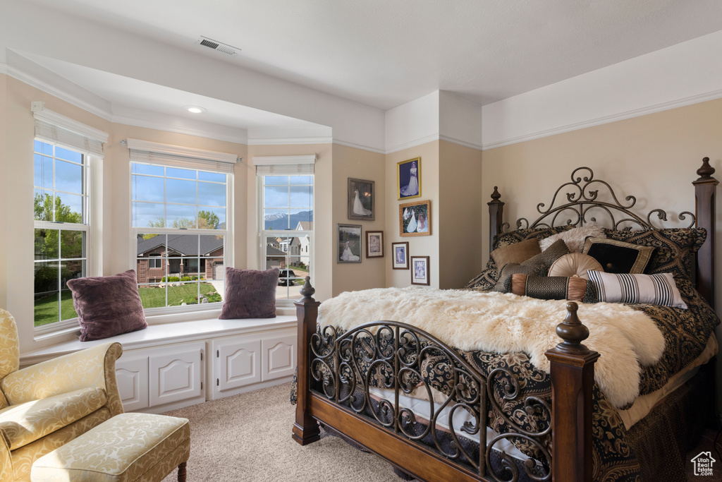 Bedroom featuring ornamental molding, light carpet, and visible vents