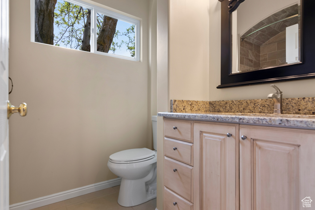 Bathroom featuring toilet, baseboards, tile patterned floors, and vanity