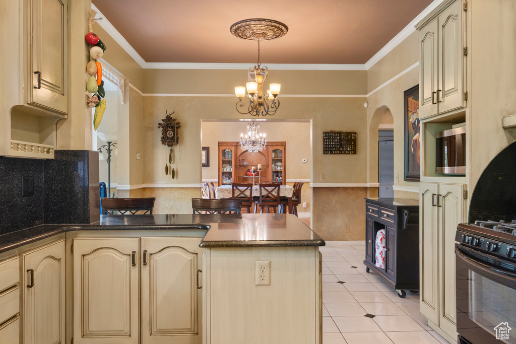 Kitchen featuring arched walkways, cream cabinets, stainless steel microwave, a peninsula, and an inviting chandelier