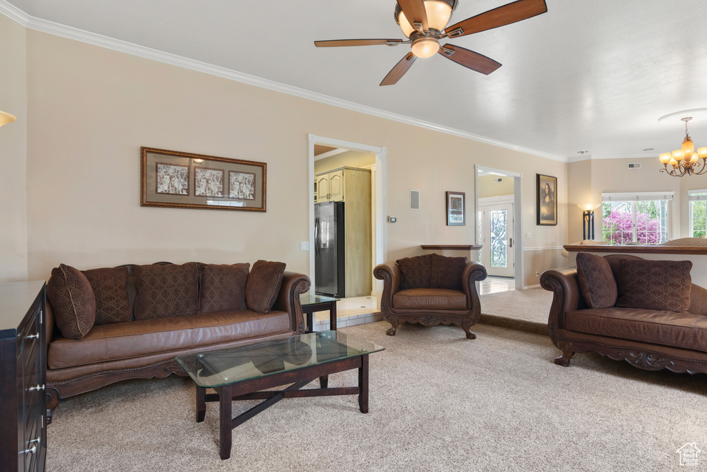 Living area featuring light colored carpet, ornamental molding, ceiling fan with notable chandelier, and visible vents