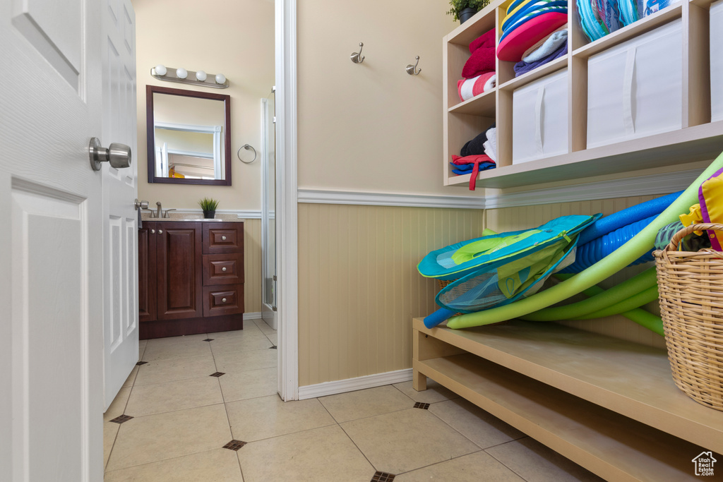 Mudroom featuring light tile patterned floors, baseboards, wainscoting, and a sink