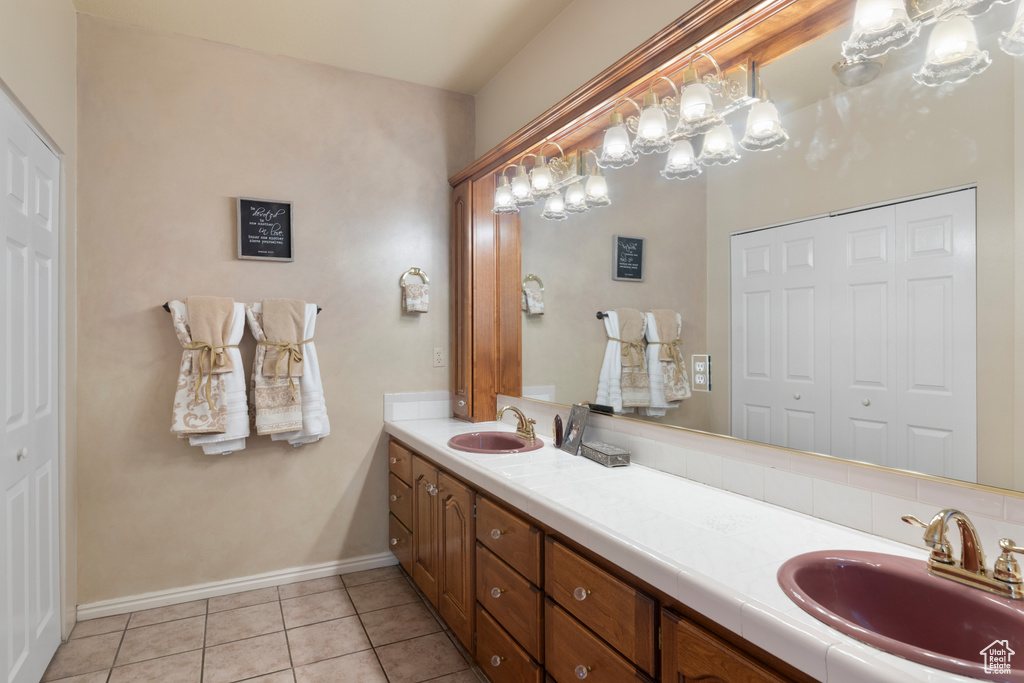 Bathroom with double vanity, a sink, baseboards, and tile patterned floors