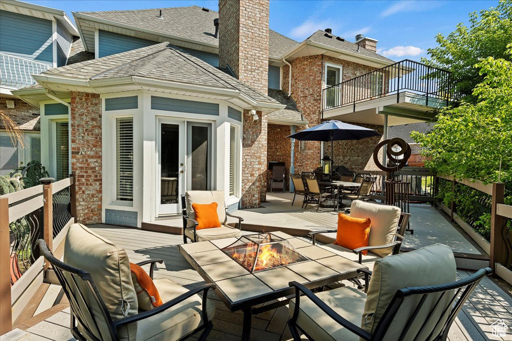 Back of house with roof with shingles, outdoor dining space, brick siding, a chimney, and a balcony
