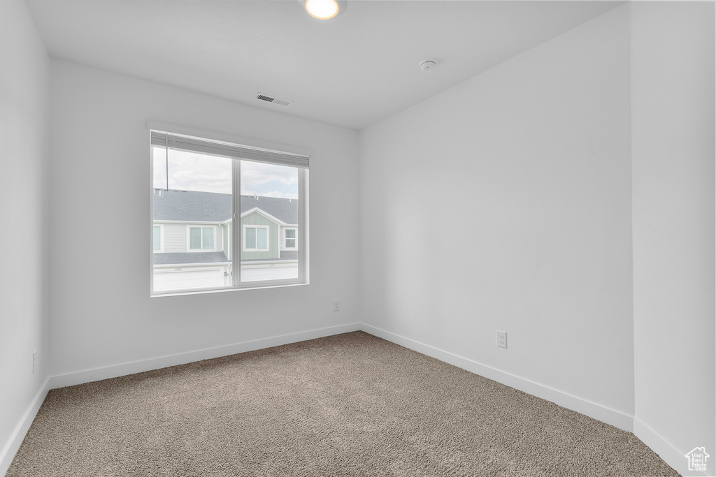 Carpeted empty room featuring baseboards and visible vents