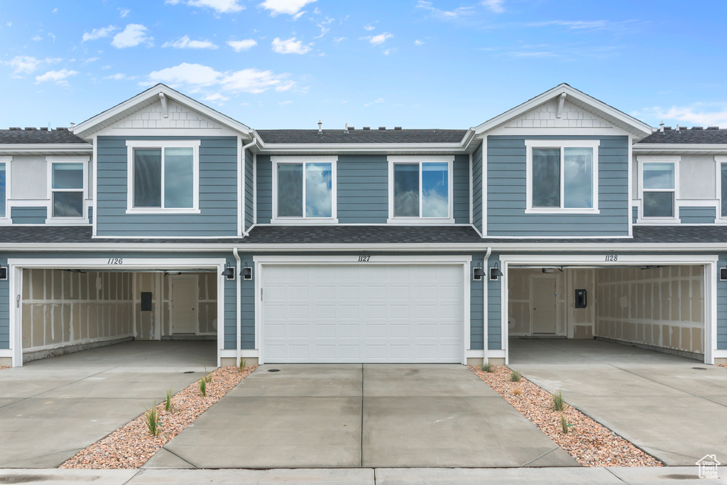 Multi unit property with driveway, a shingled roof, and a garage