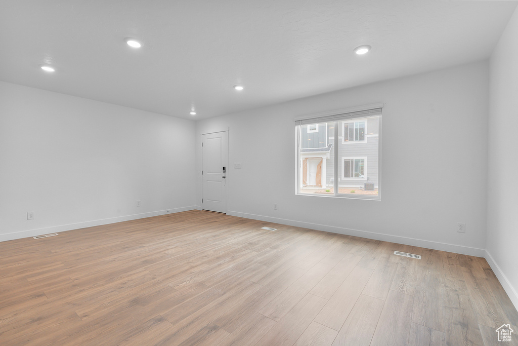 Empty room with recessed lighting, baseboards, light wood-type flooring, and visible vents