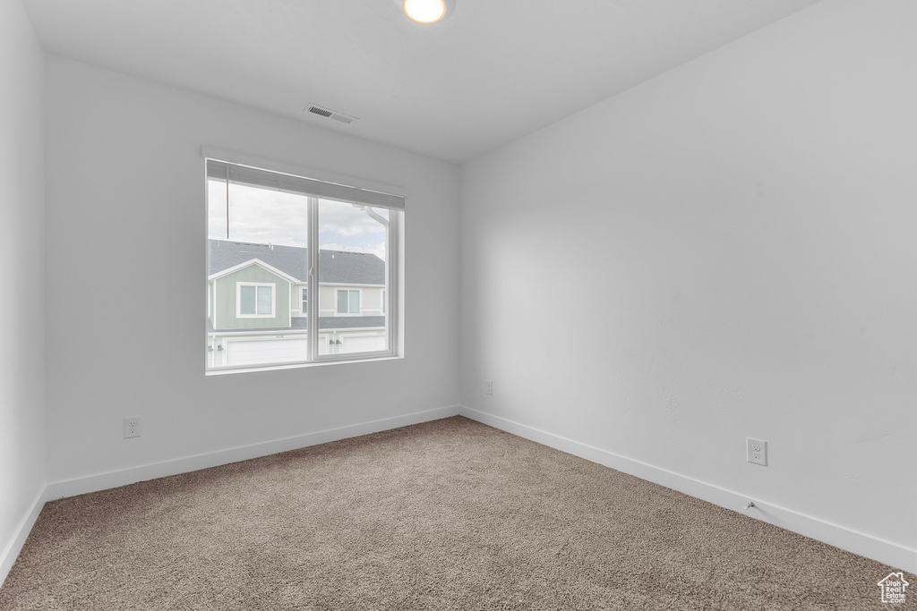 Carpeted empty room featuring visible vents and baseboards