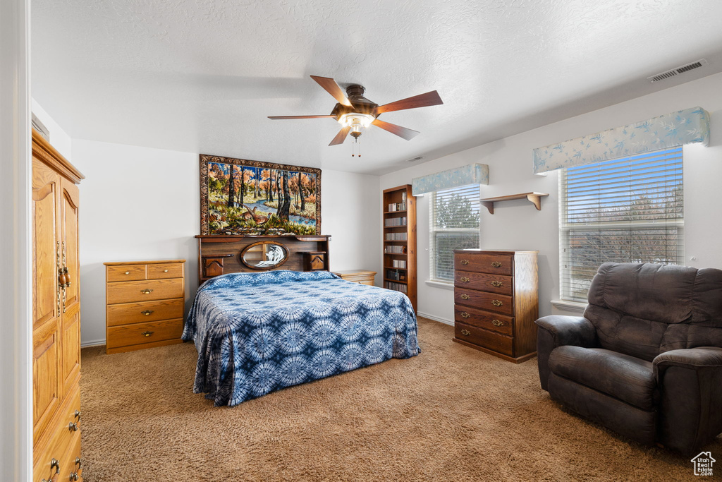 Carpeted bedroom with baseboards, ceiling fan, and visible vents