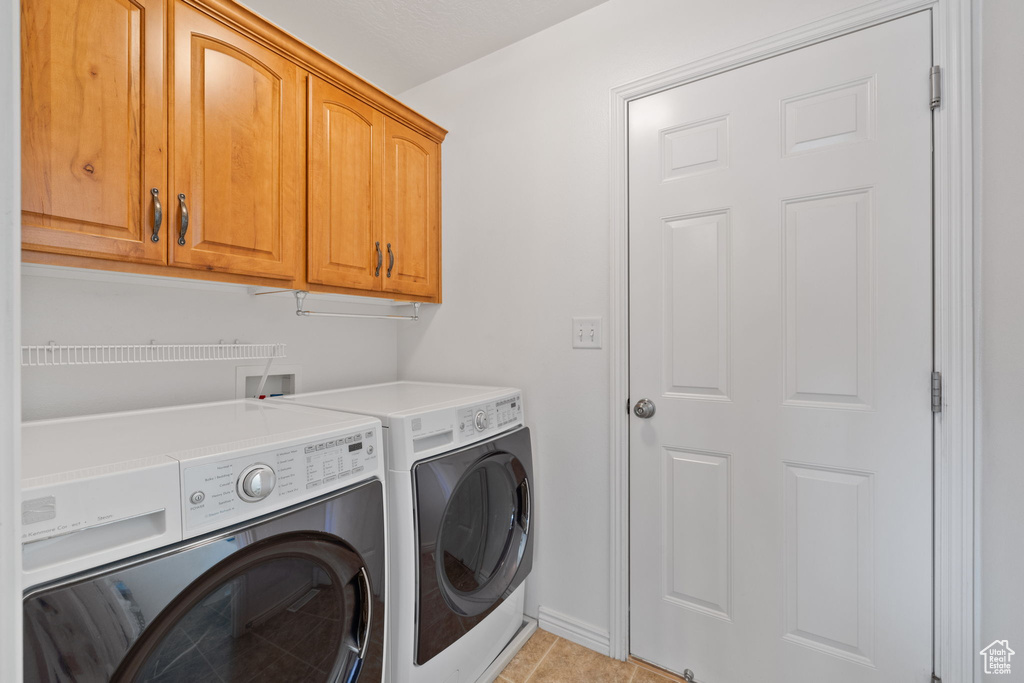 Laundry room with cabinet space, baseboards, and washer and clothes dryer