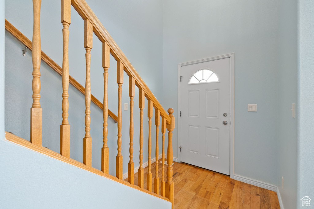 Foyer entrance featuring light wood-style floors, baseboards, a towering ceiling, and stairs
