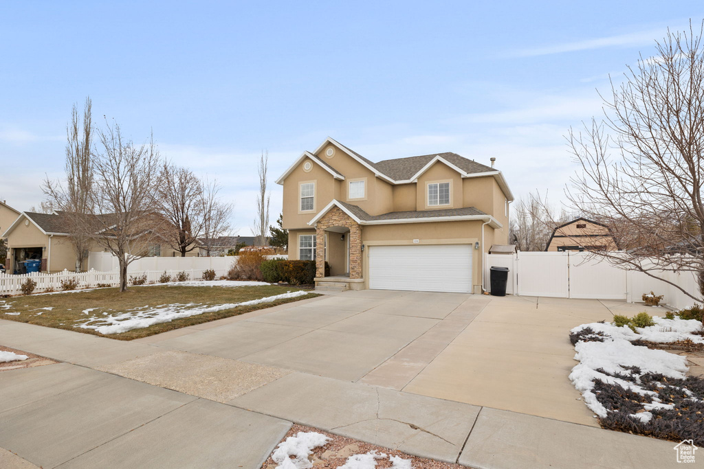 Traditional-style house with a garage, fence, stone siding, stucco siding, and concrete driveway