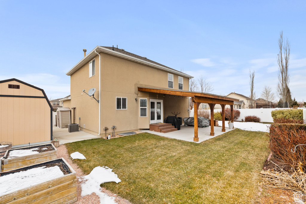 Back of property featuring an outdoor structure, a patio, a fenced backyard, a storage unit, and a yard
