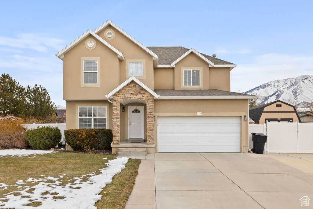 Traditional-style home with fence, stucco siding, an attached garage, a mountain view, and driveway