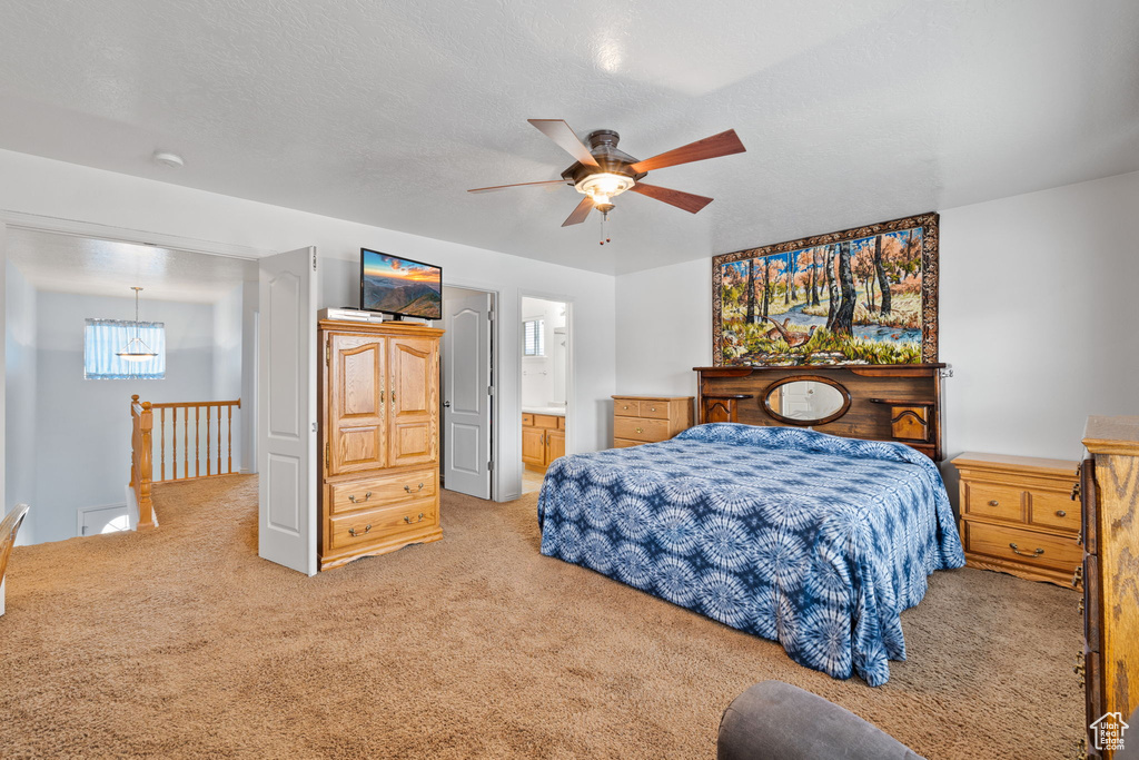 Bedroom with connected bathroom, carpet, and ceiling fan with notable chandelier