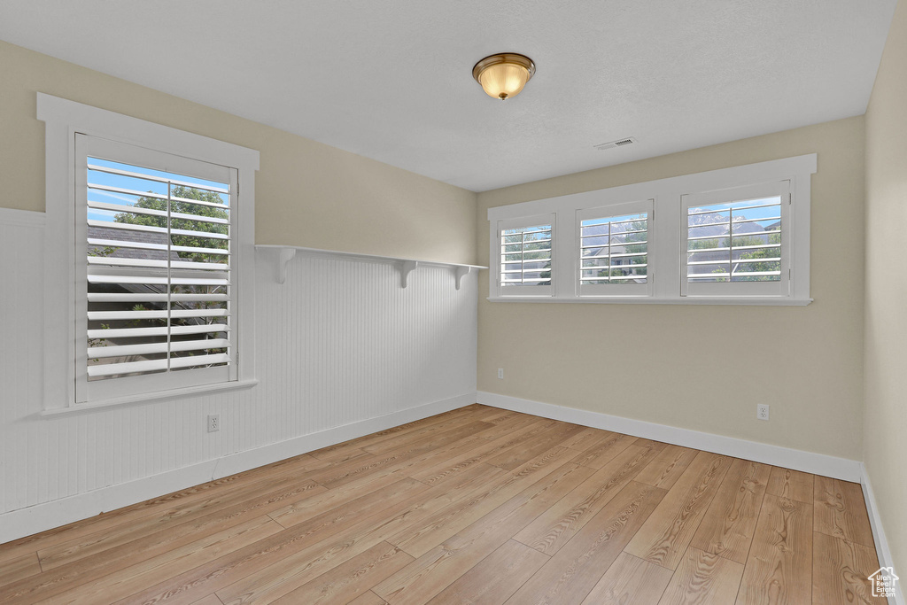 Unfurnished room with wainscoting, a wealth of natural light, and hardwood / wood-style flooring