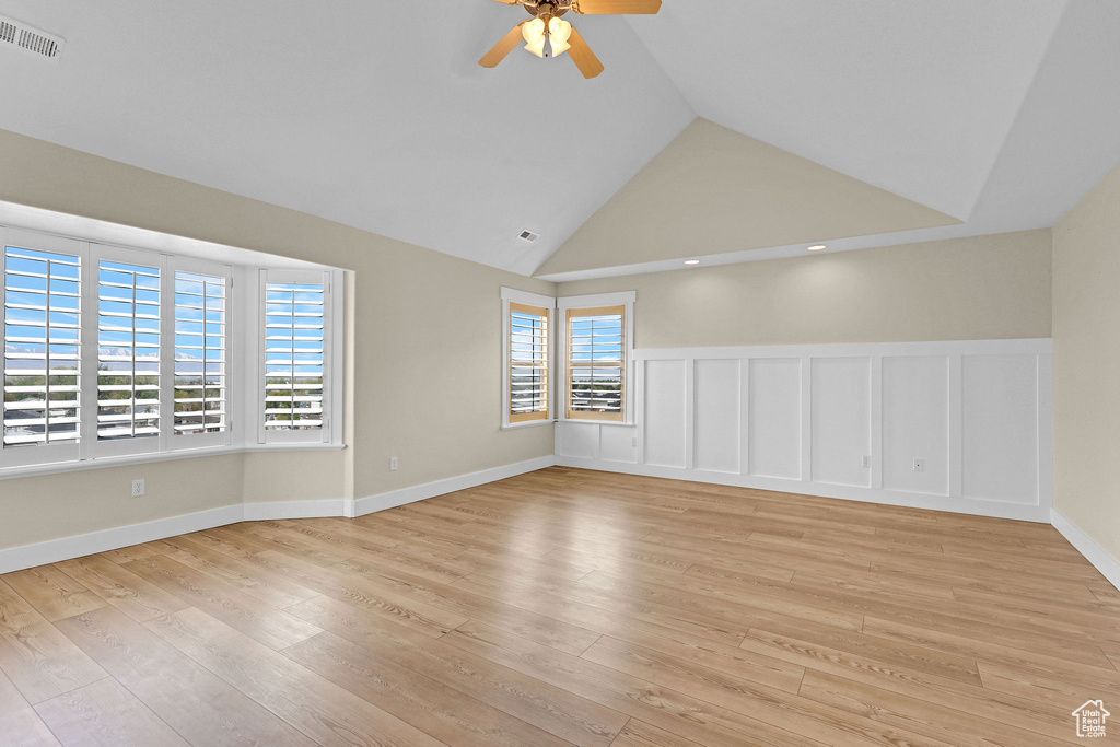 Empty room featuring visible vents, light wood finished floors, ceiling fan, and high vaulted ceiling