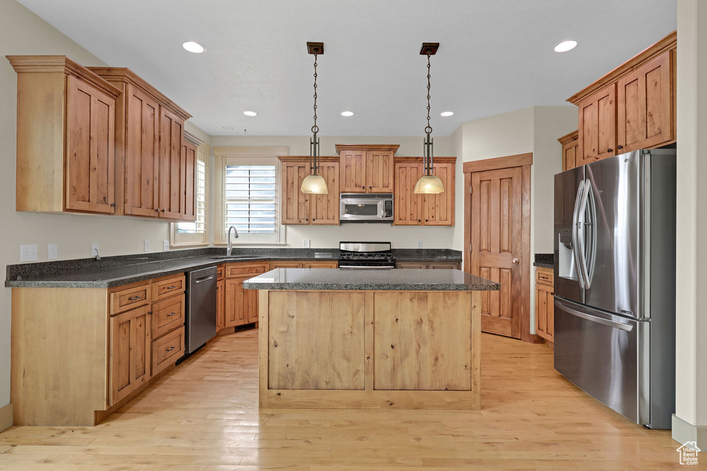 Kitchen with appliances with stainless steel finishes, a sink, light wood-style floors, recessed lighting, and a kitchen island