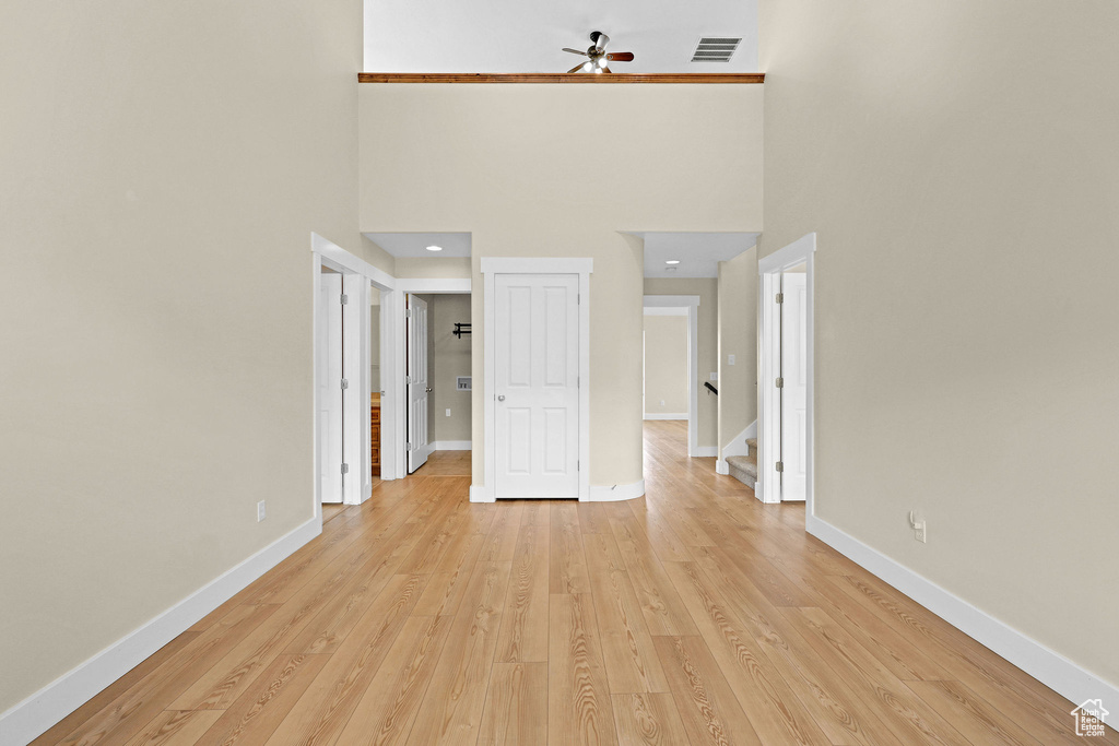 Interior space featuring a towering ceiling, baseboards, a ceiling fan, and visible vents