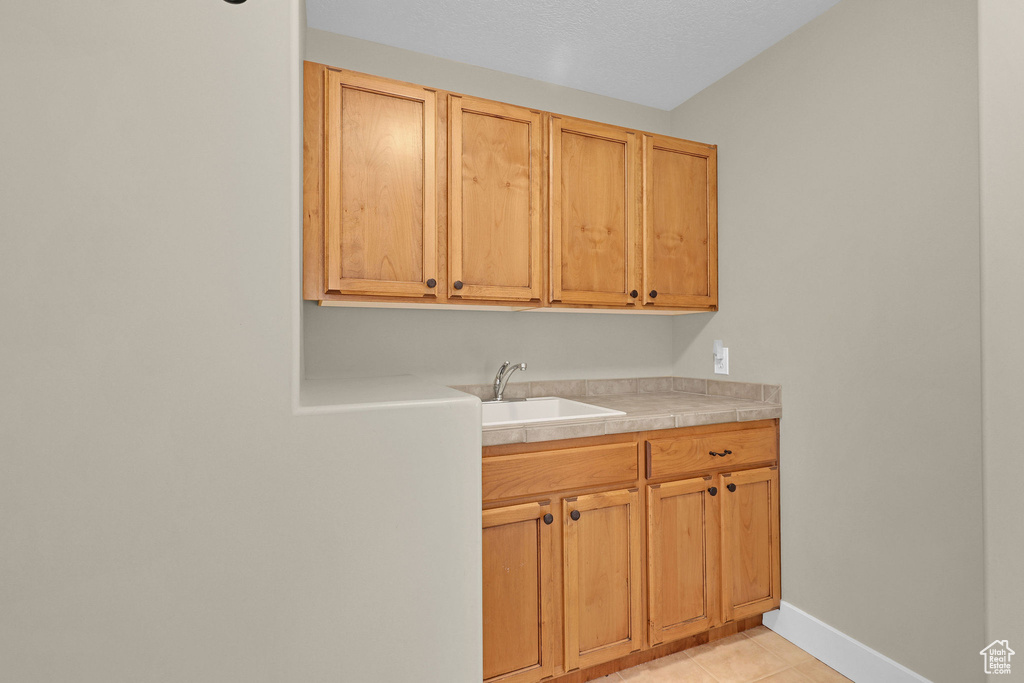 Interior space with light tile patterned floors, baseboards, and a sink