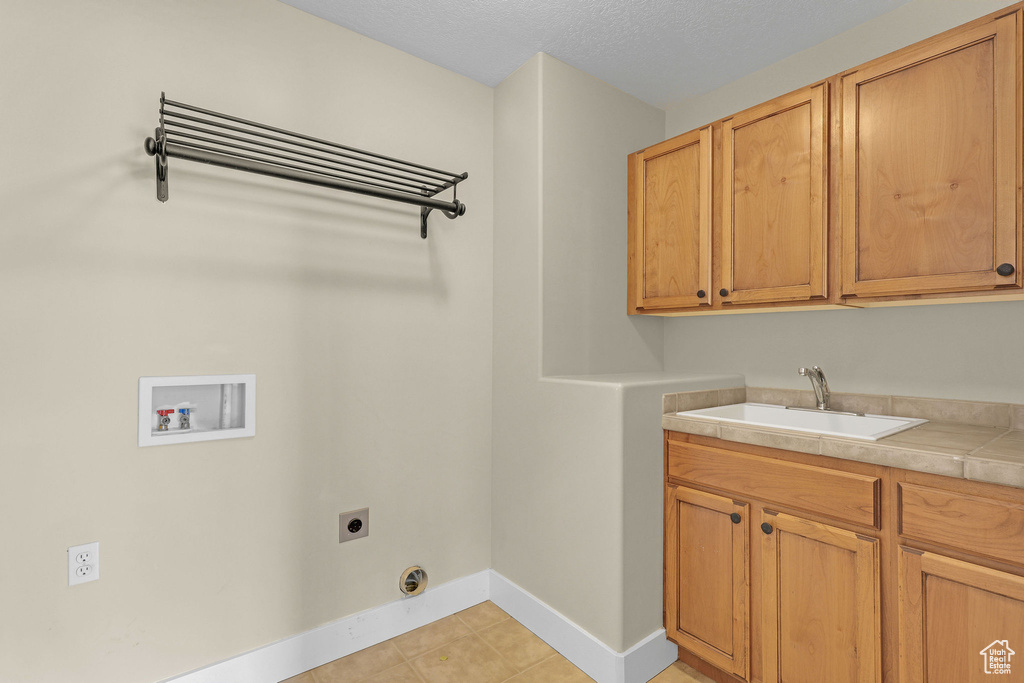 Laundry room featuring baseboards, electric dryer hookup, a sink, cabinet space, and washer hookup