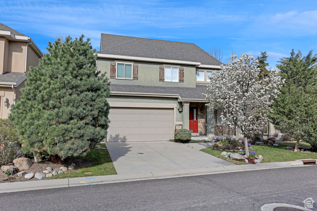 View of front of house featuring a garage, stucco siding, driveway, and roof with shingles