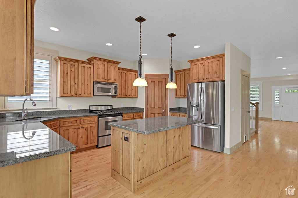Kitchen featuring appliances with stainless steel finishes, a center island, a sink, recessed lighting, and light wood-style flooring