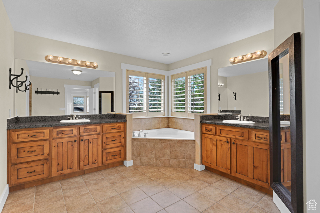 Bathroom featuring tile patterned flooring, a sink, a bath, and two vanities