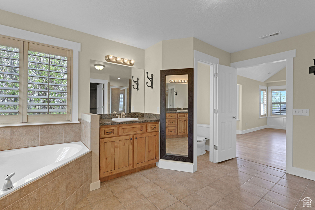 Full bath featuring visible vents, a garden tub, tile patterned flooring, vanity, and toilet