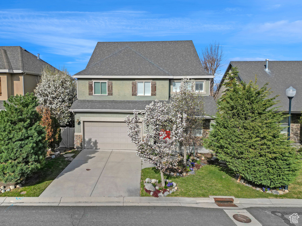 View of front facade with a garage, stucco siding, driveway, and a shingled roof