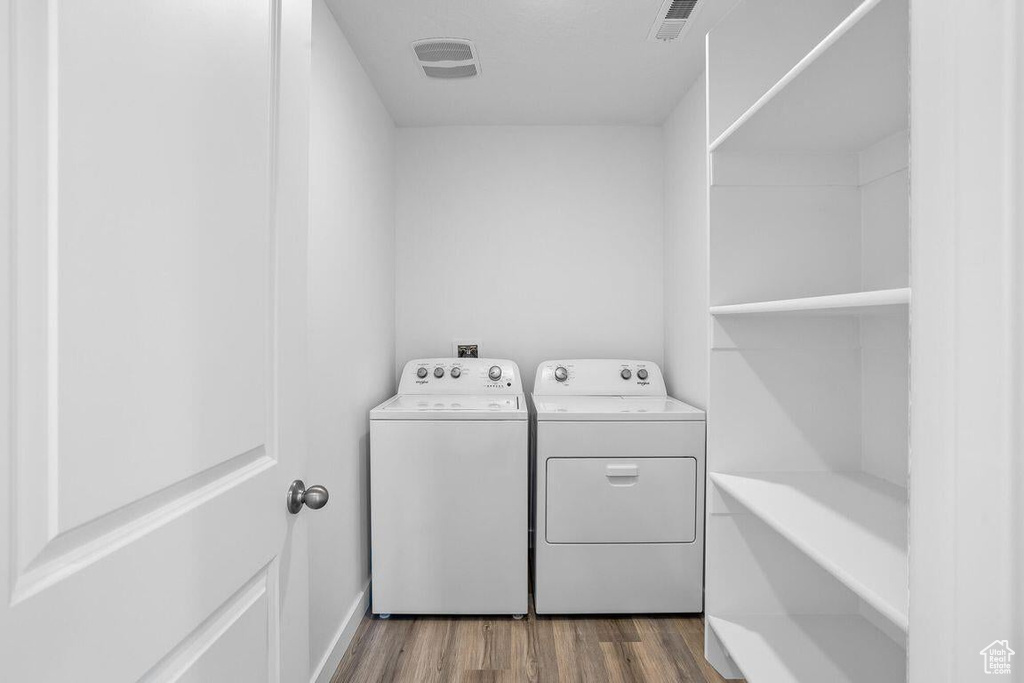 Laundry area with washing machine and clothes dryer, laundry area, dark wood finished floors, and visible vents