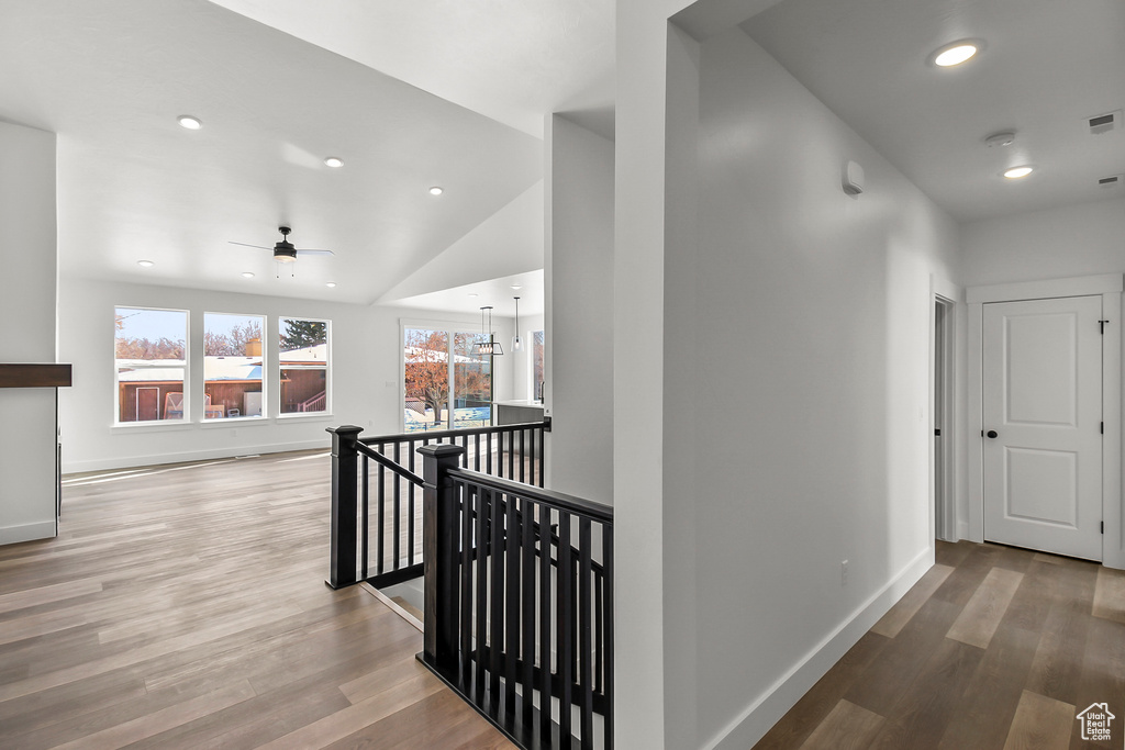 Corridor with recessed lighting, an upstairs landing, wood finished floors, and lofted ceiling