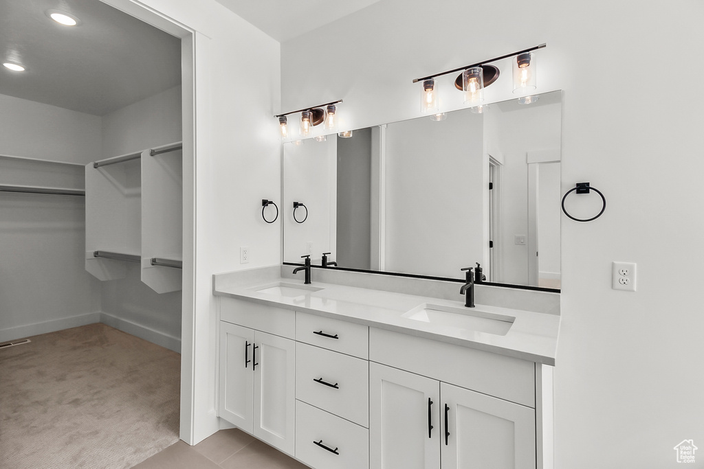 Bathroom with a sink, baseboards, double vanity, and a spacious closet