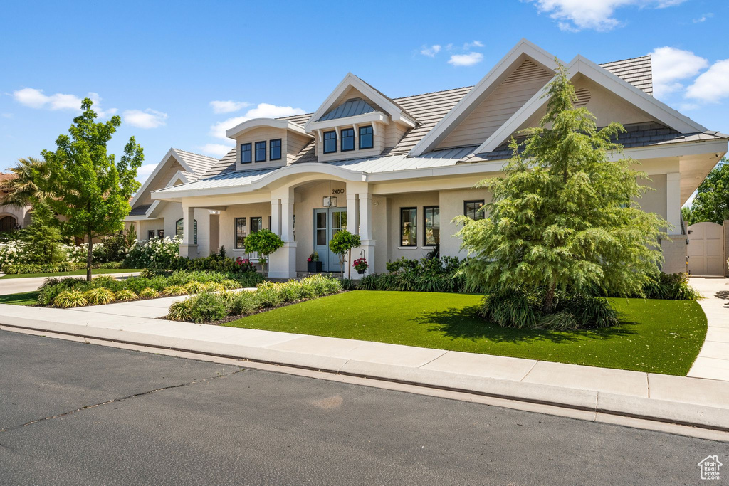 Craftsman-style home with stucco siding, a front yard, and metal roof