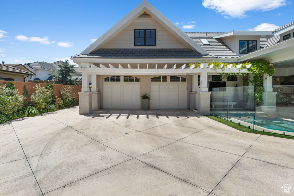 View of front of home featuring fence, a tile roof, and a garage