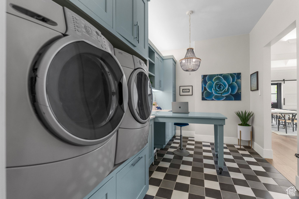 Washroom featuring cabinet space, independent washer and dryer, baseboards, and a chandelier