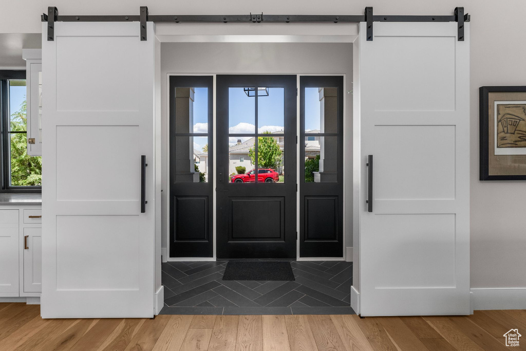 Entryway featuring baseboards, a barn door, and light wood-style floors
