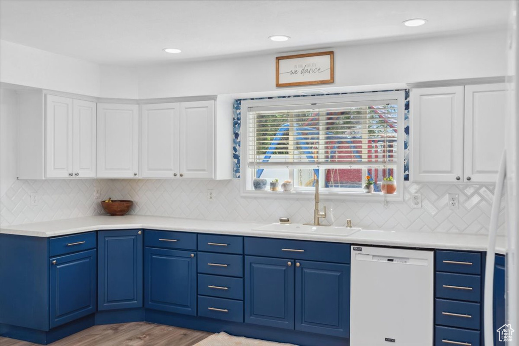 Kitchen featuring dishwasher, a sink, light countertops, white cabinets, and light wood-style floors