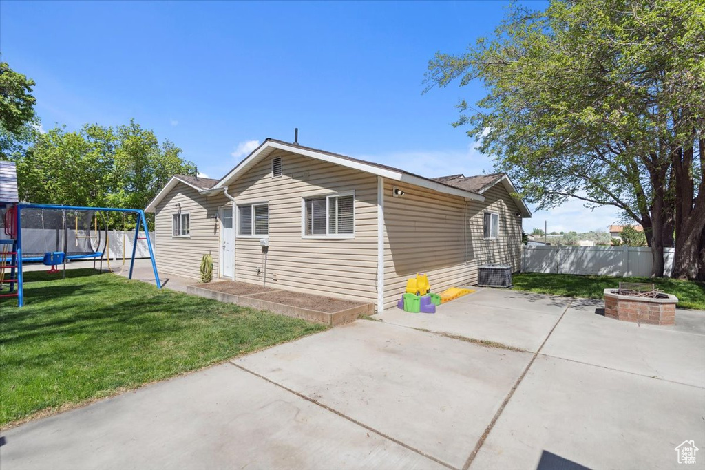 Bungalow with fence, a front yard, cooling unit, a patio, and a trampoline