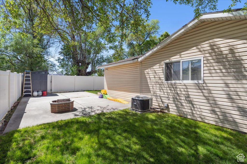 View of yard with a fenced backyard, a patio area, an outdoor fire pit, and cooling unit