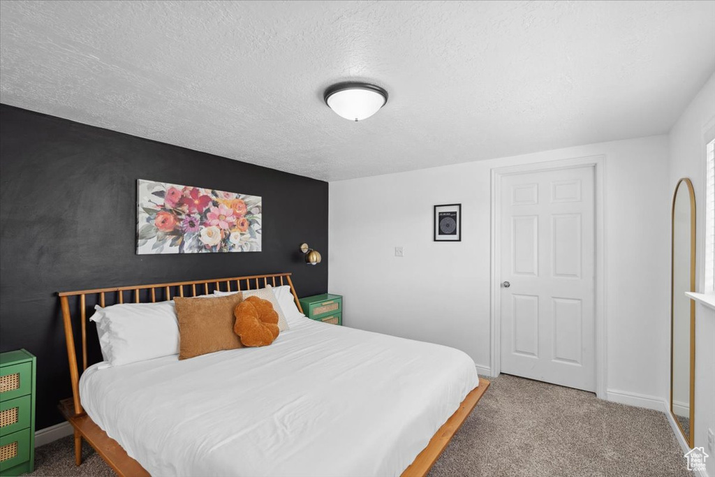 Carpeted bedroom featuring baseboards and a textured ceiling