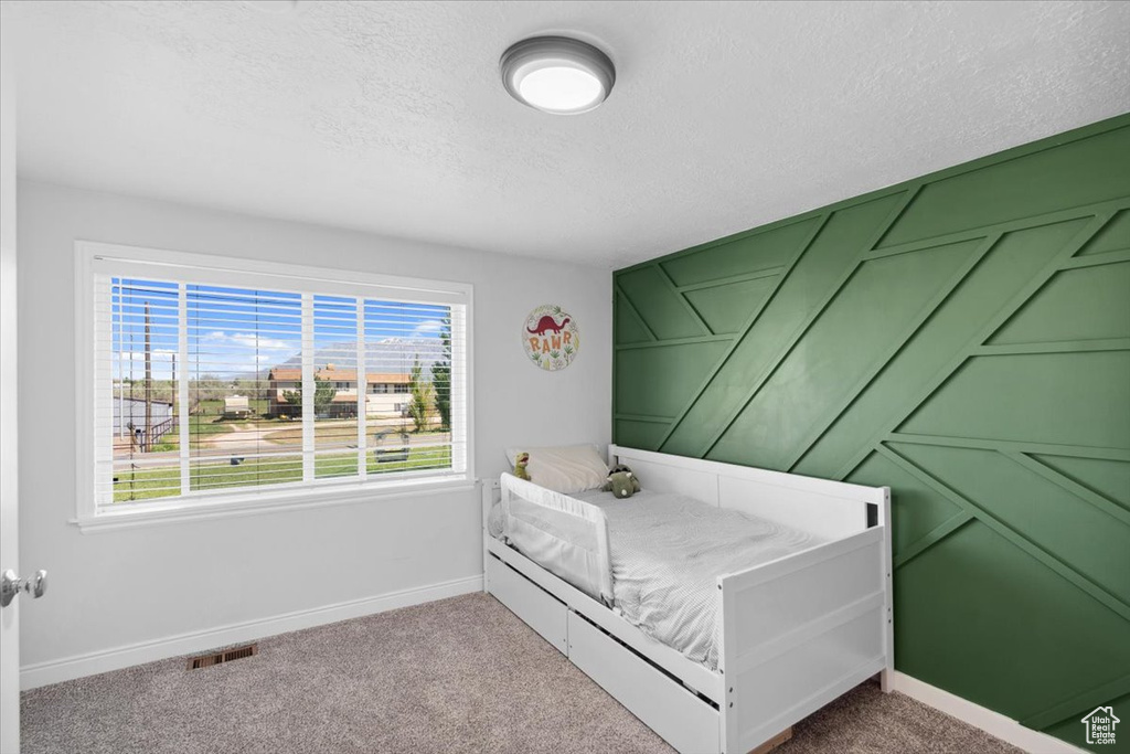 Bedroom with baseboards, carpet floors, a textured ceiling, and visible vents