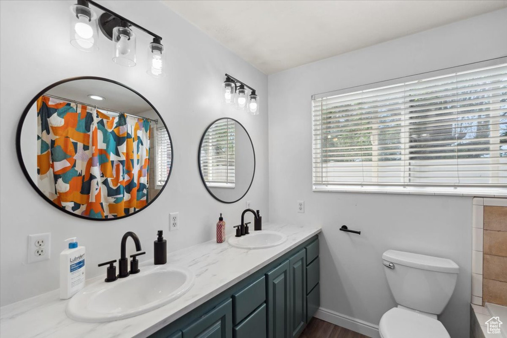 Full bath with double vanity, toilet, a shower with curtain, and a sink