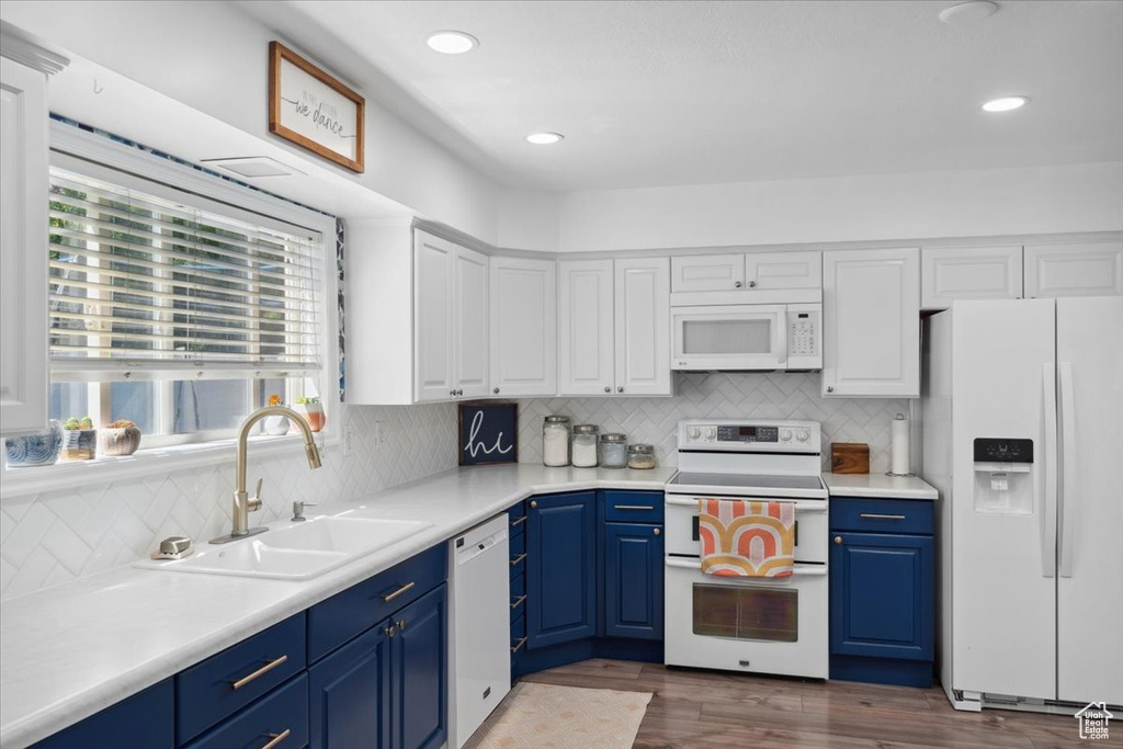 Kitchen featuring a sink, blue cabinets, white cabinets, and white appliances