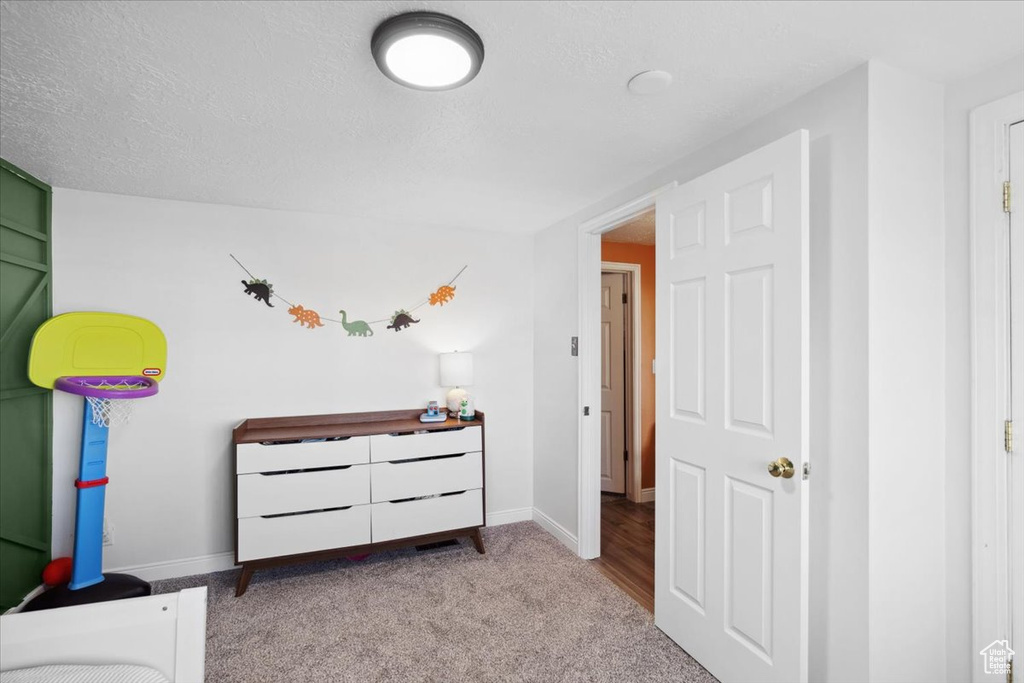 Carpeted bedroom featuring baseboards and a textured ceiling