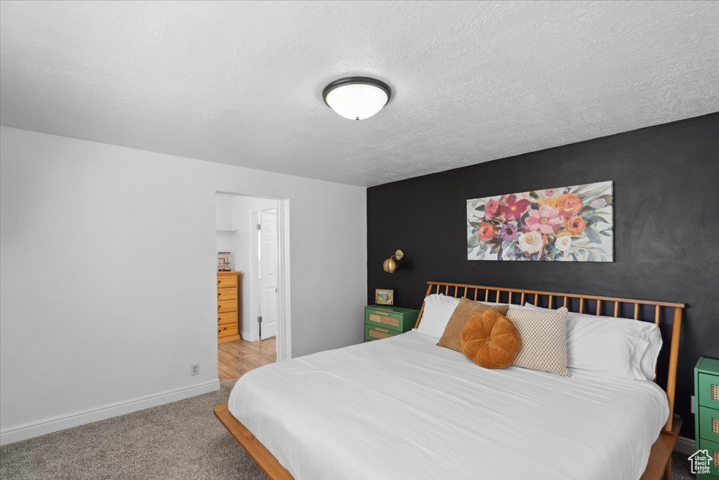 Carpeted bedroom featuring baseboards and a textured ceiling